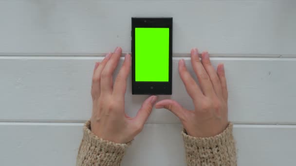 Женщина смотрит на смартфон с зеленым экраном — стоковое видео