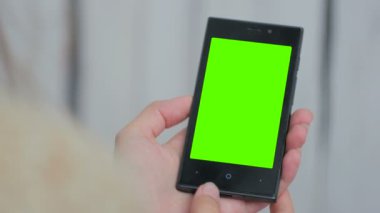 Yeşil ekranlı akıllı telefona bakan kadın