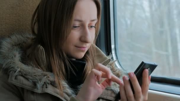 Zamyšlená žena cestující ve vlaku a pomocí chytrého telefonu — Stock video