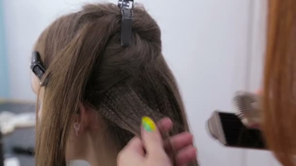 Профессиональный парикмахер делает прическу для молодой красивой женщины с длинными волосами — стоковое видео