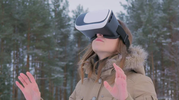 Woman using virtual reality glasses in winter forest