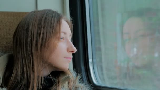Zamyšlená žena uvolňující a při pohledu z okna vlaku — Stock video