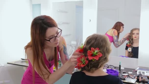 Cabeleireiro, cabeleireiro acabamento penteado criativo com flores para menina adolescente — Vídeo de Stock