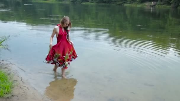 Μυστηριώδες κορίτσι με δημιουργικό μακιγιάζ σε εθνοτικές κόκκινο φόρεμα, το περπάτημα στο νερό — Αρχείο Βίντεο