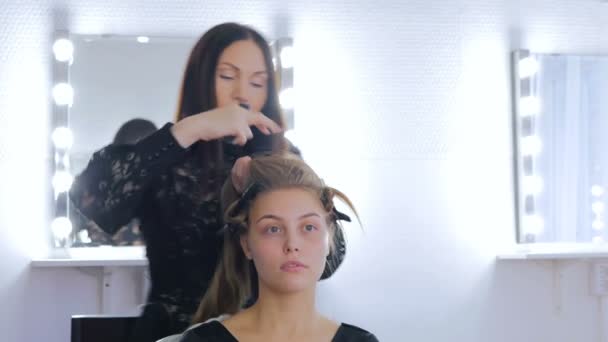 Cabeleireiro profissional fazendo penteado para jovem mulher bonita — Vídeo de Stock