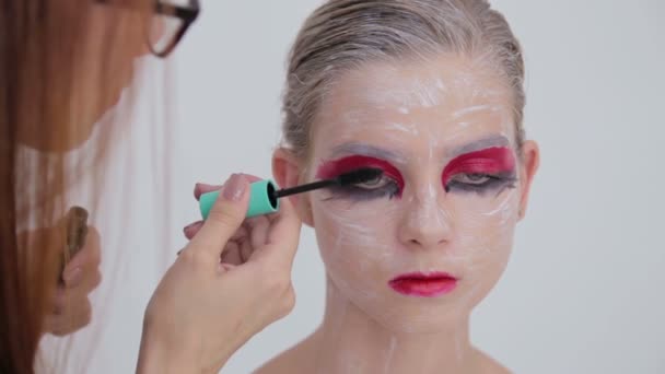 Professional make-up artist applying mascara on eyelashes of model — Stock Video