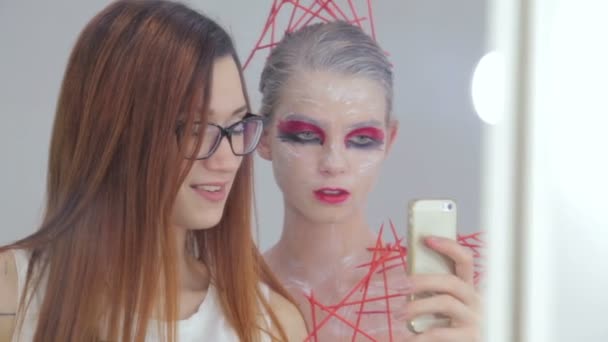 Maquiagem artista e seu cliente com maquiagem incomum criativo tirar selfie — Vídeo de Stock