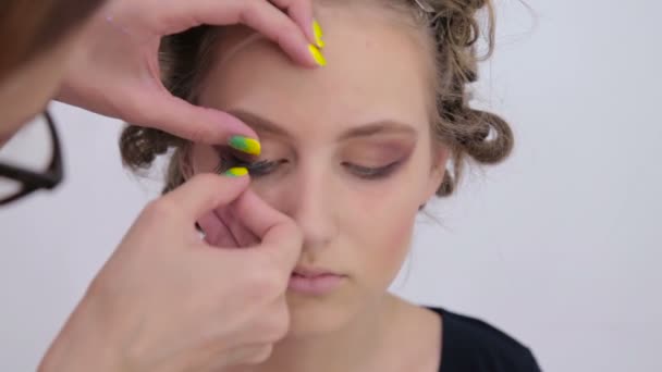 Professionelle Visagistin trägt falsche Wimpern auf die Augen der Models auf — Stockvideo