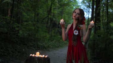 Karanlık ormanda iki yanan mum tutan yaratıcı makyajlı alışılmadık kız