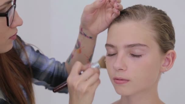 5 Schüsse. Make-up-Artist trägt flüssiges Tonfundament auf Mädchengesicht auf — Stockvideo