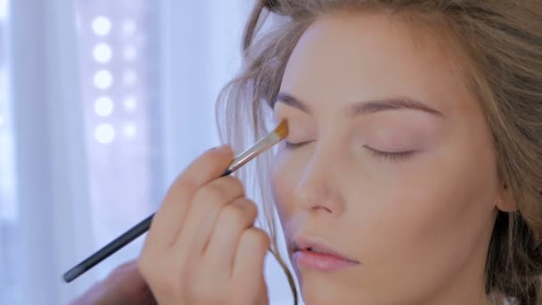 Professional make-up artist applying cream base eyeshadow primer to model eye — Stock Video