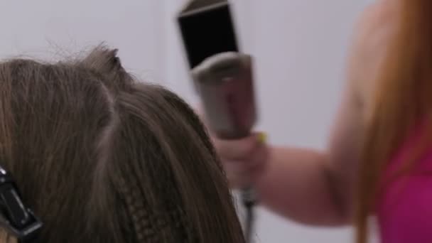 Hairdresser using straightener on long hair of client in hair salon — Stock Video