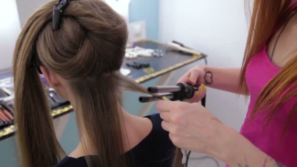 Профессиональный парикмахер делает прическу для красивой девушки-подростка - делает кудри — стоковое видео