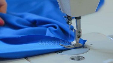 Profesyonel terzi, moda tasarımcısı dikiş makinesiyle elbise dikiyor.