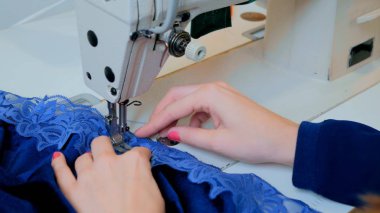 Profesyonel terzi, moda tasarımcısı dikiş makinesiyle elbise dikiyor.