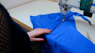 Profesyonel terzi, moda tasarımcısı dikiş makinesiyle elbise dikiyor.