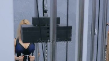 Sporcu genç kadın spor aletleri üzerinde çalışıyor.