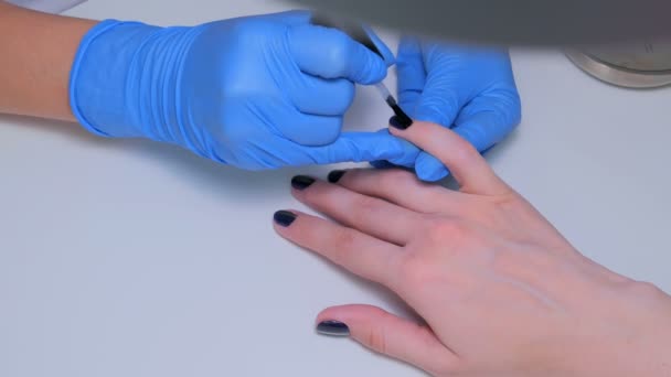 Професійний косметолог наносить лак для нігтів на жіночий ніготь — стокове відео