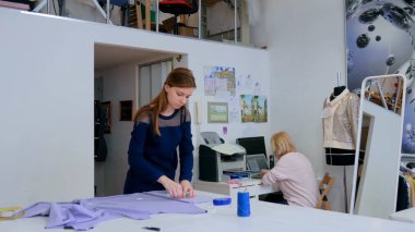 Terzi, tasarımcı dikiş atölyesinde kumaş ölçümü yapıyor.