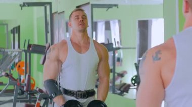 Spor salonunda halter kaldırma atletik genç adam