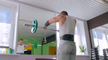 Halter vasıl jimnastik salonu, fitness kulübü ile egzersizleri yapıyor atletik genç adam