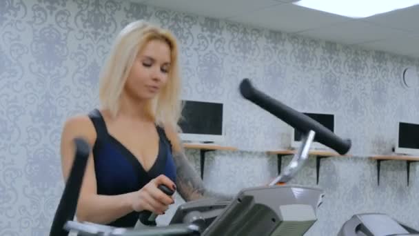 Атлетичная молодая женщина работает на шаговую машину в тренажерном зале — стоковое видео