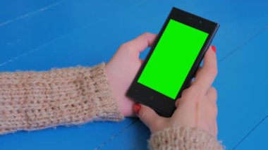 Yeşil ekranlı akıllı telefona bakan kadın