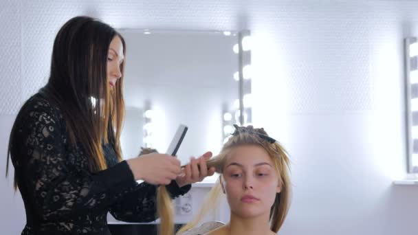 Frisören använder plattång på långt hår client i frisersalong — Stockvideo