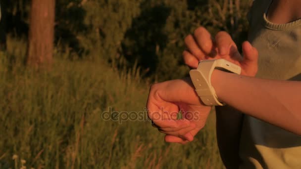 Mujer deportiva usando reloj inteligente portátil al atardecer — Vídeos de Stock