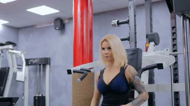 Atletische jonge vrouw die traint op fitnesstoestellen — Stockvideo