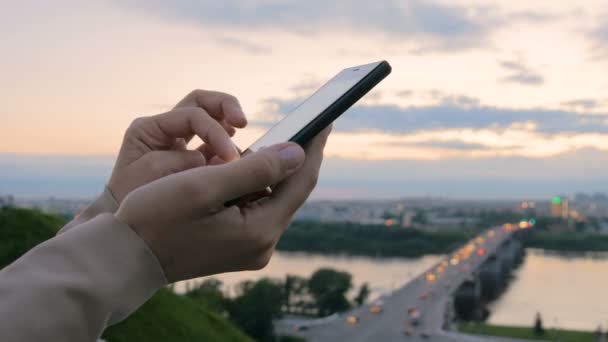 Nő használ smartphone a város naplemente után — Stock videók