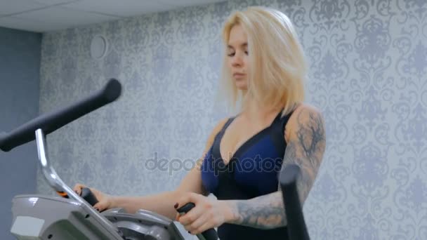 Atlética mujer joven haciendo ejercicio en la máquina de pasos en el gimnasio — Vídeos de Stock