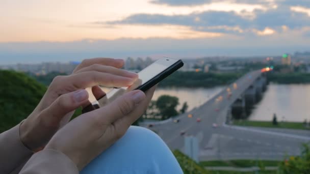 Gün batımından sonra şehirde Smartphone kullanan kadın — Stok video