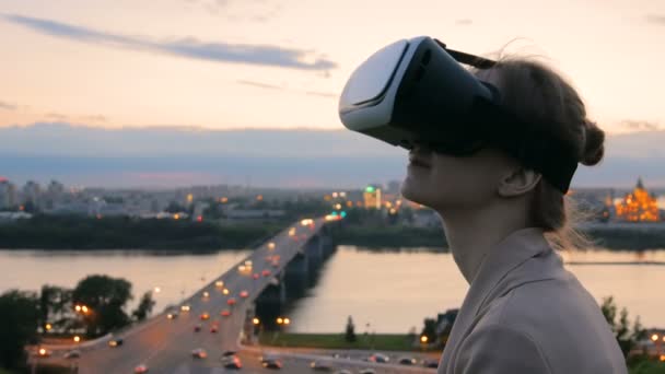 Vrouw maakt gebruik van virtual reality-bril in de stad na zonsondergang — Stockvideo