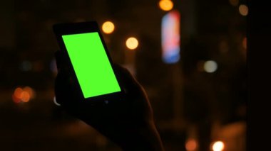 Yeşil ekranlı akıllı telefona bakan kadın