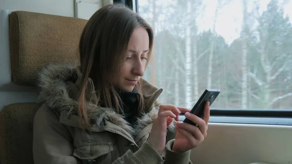 Mulher pensativa viajando em um trem e usando um smartphone — Fotografia de Stock