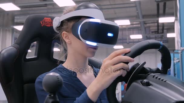 Молодая женщина, использующая гарнитуру виртуальной реальности и играющая в симуляторе привода автомобиля — стоковое видео
