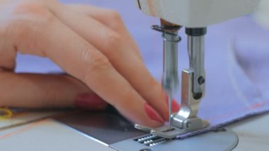 Profesyonel terzi, moda tasarımcısı dikiş makinesiyle elbise dikiyor.