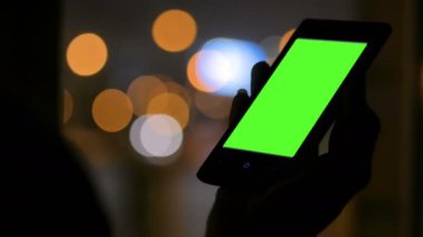 Yeşil ekranlı akıllı telefona bakan kadın