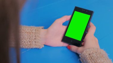 Yeşil ekranlı akıllı telefona bakan kadın