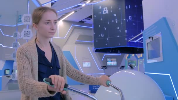 Ung kvinna med hjälp av interaktiv cykel simulator maskin — Stockvideo