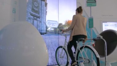 Etkileşimli bisiklet simülatörü kullanan genç bir kadın