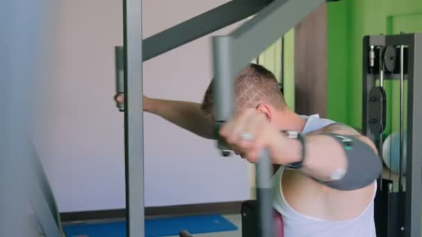 Αθλητική νεαρός χρησιμοποιώντας μηχανή άσκηση στο γυμναστήριο — Αρχείο Βίντεο