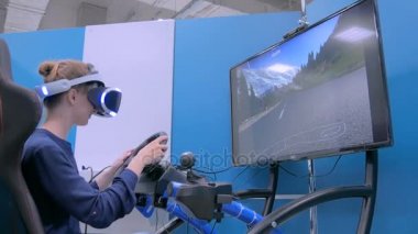 Sanal gerçeklik kulaklığı kullanan ve araba sürücüsü simülatöründe oynayan genç bir kadın.