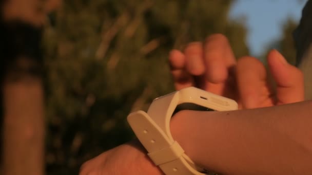 Mujer joven usando reloj inteligente portátil al atardecer — Vídeos de Stock