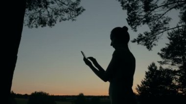 Gün batımından sonra parkta Smartphone kullanan kadın