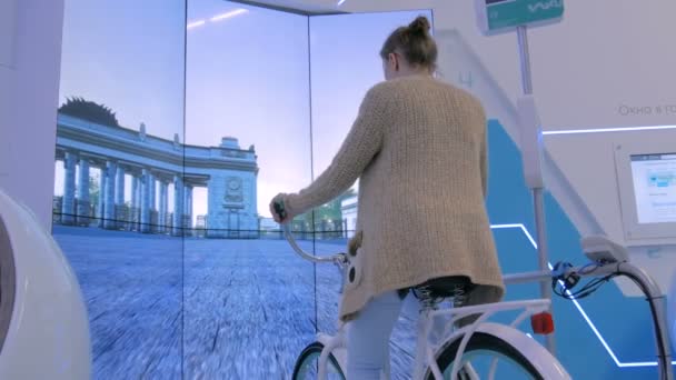 Молода жінка використовує інтерактивну машину симулятора велосипеда — стокове відео