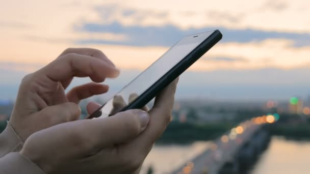 Woman using smartphone in the city after sunset — Stock Video