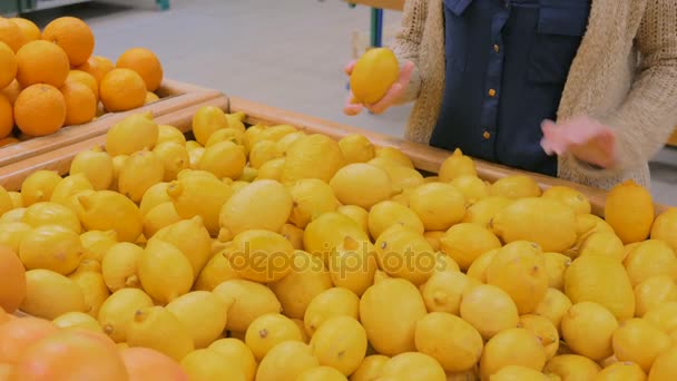 Женщина покупает свежие желтые лимоны в продуктовом магазине — стоковое видео