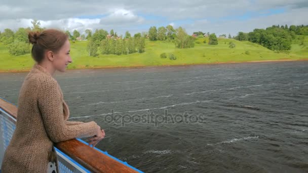 Jonge vrouw staande op het dek van het cruiseschip en kijken naar de rivier en landschap — Stockvideo